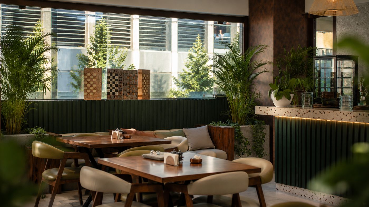 Lounge corner with green leather chairs, palms and backgammon boards on the window ledge